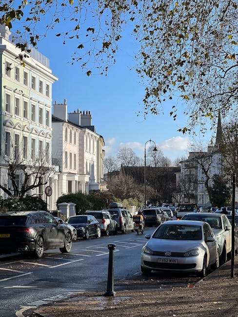 A street scene along Upper Richmond Road SW15 with residential buildings on the left featuring classic architectural details and white facades. Parked cars, including sedans and SUVs, line both sides